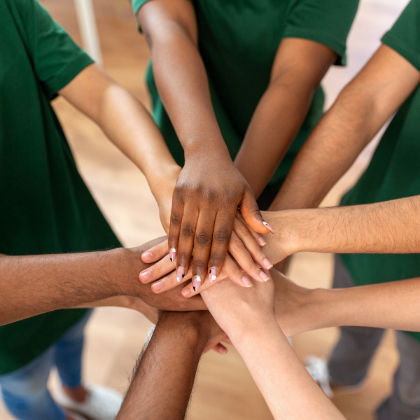 Hands stacked on top of each other in center of group