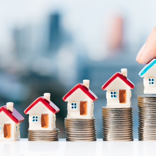 Small house figurines placed upon stacks of coins