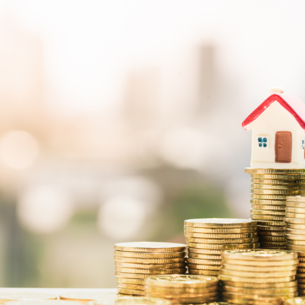 Small house figurine placed upon stacks of coins